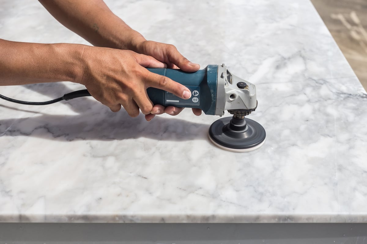 Man polishing marble stone by small angle grinder